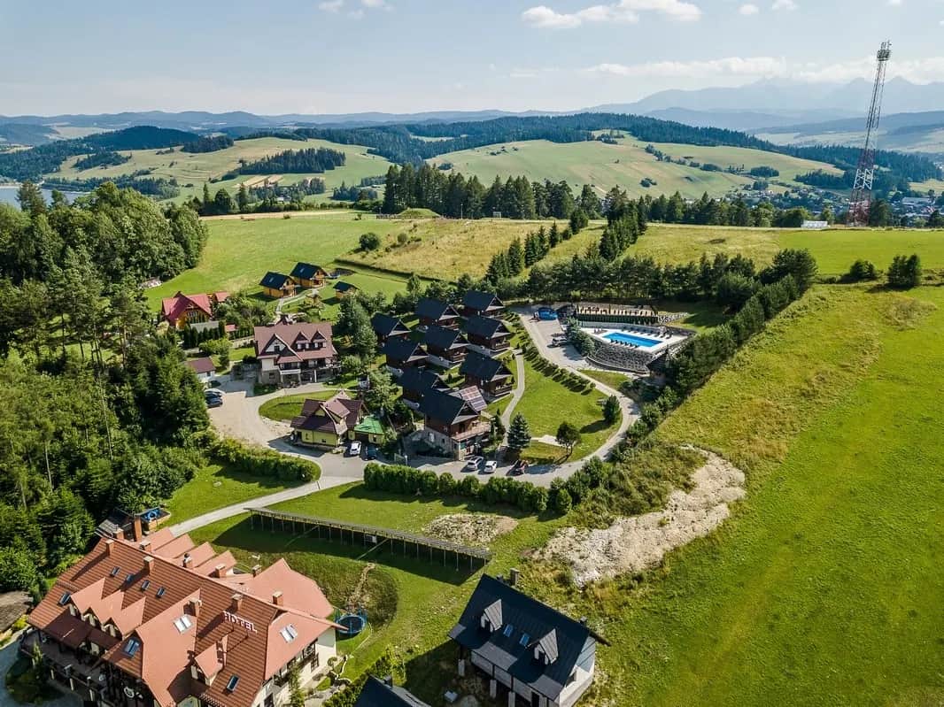 Ujęcie z drona na domki i basen z pasmami gór w tle