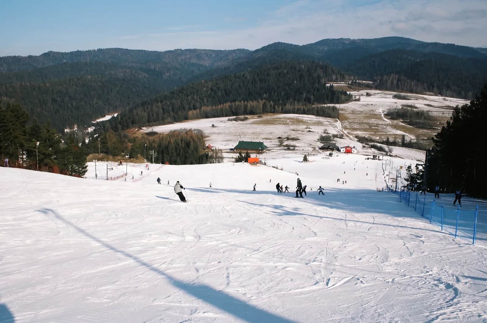 Zimowe stoki Czorsztyn-Ski na górze Wdżar z koleją krzesełkową, turkusowe Jezioro Czorsztyńskie i zamek w Niedzicy oraz panorama Tatr w tle
