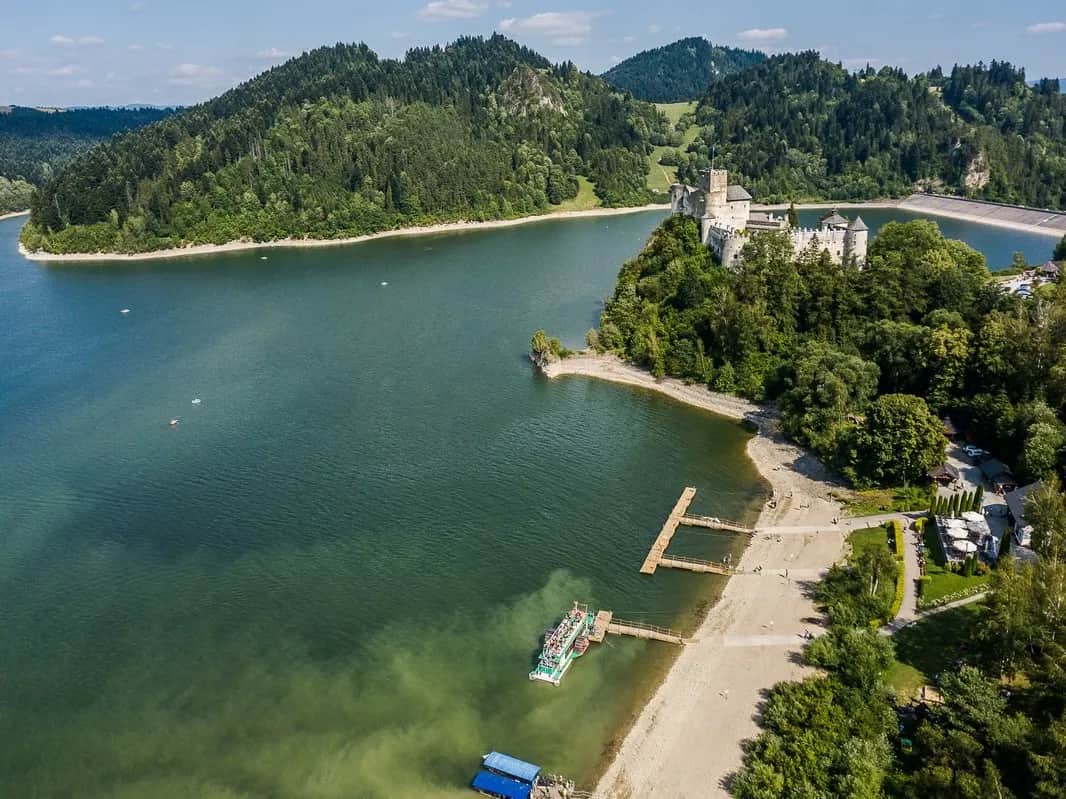 Jezioro z zamkiem na brzegu i pasmami Tatr na horyzoncie