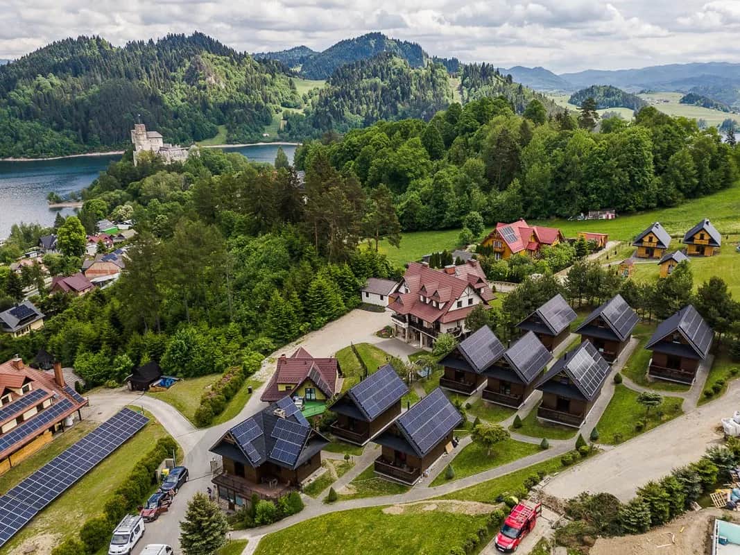 Widok z lotu ptaka na domki resortu z zamkiem nad jeziorem w tle