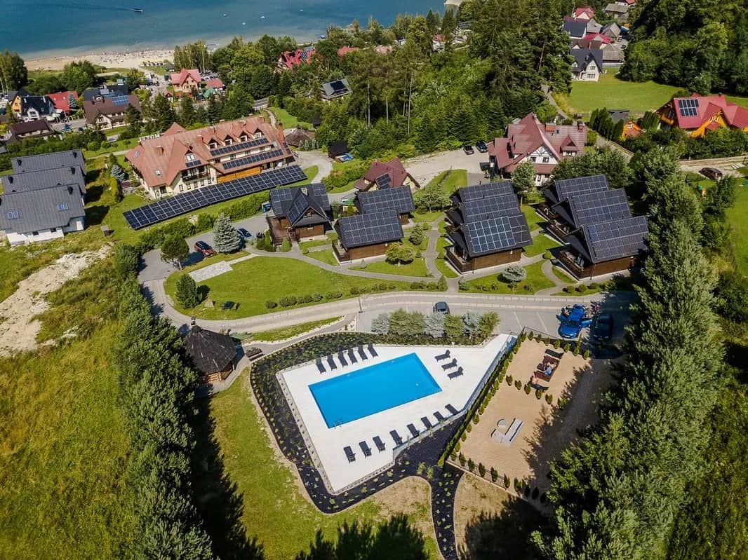 Widok z lotu ptaka na resort Mergen z drewnianymi domkami, basenem i jeziorem w tle