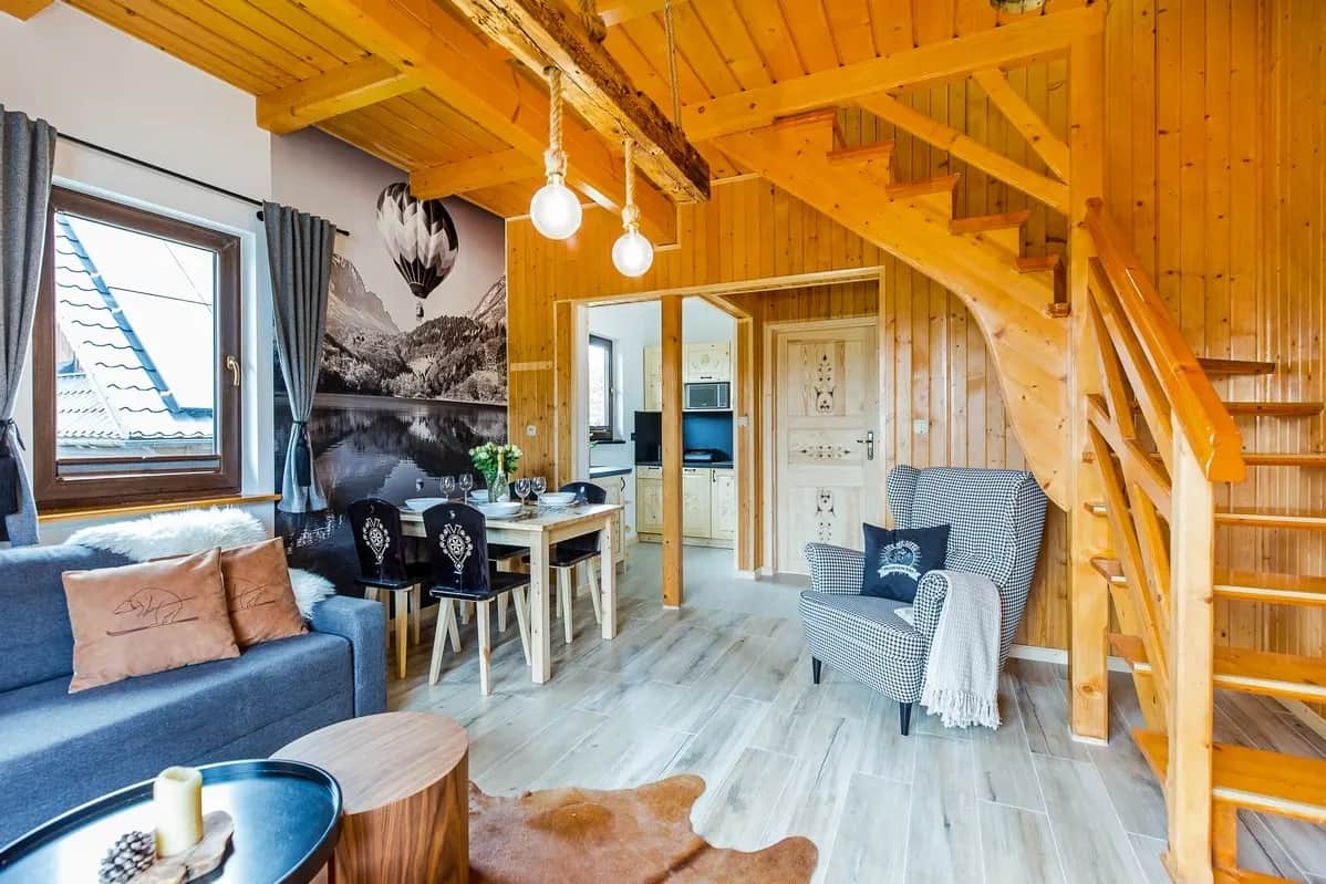 Salon w stylu góralskim z sofą, stołem i klatką schodową