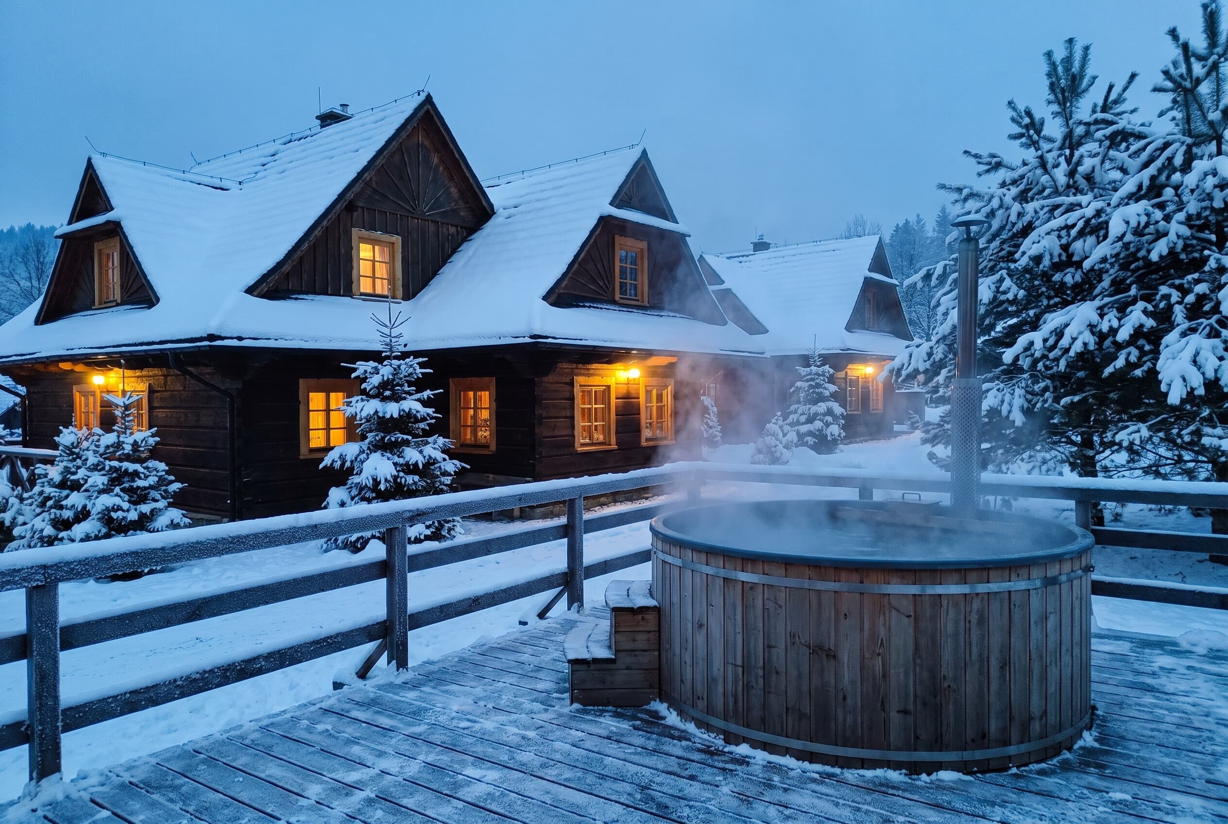 Zimowy wieczór - ośnieżone domki i parujące jacuzzi na tarasie
